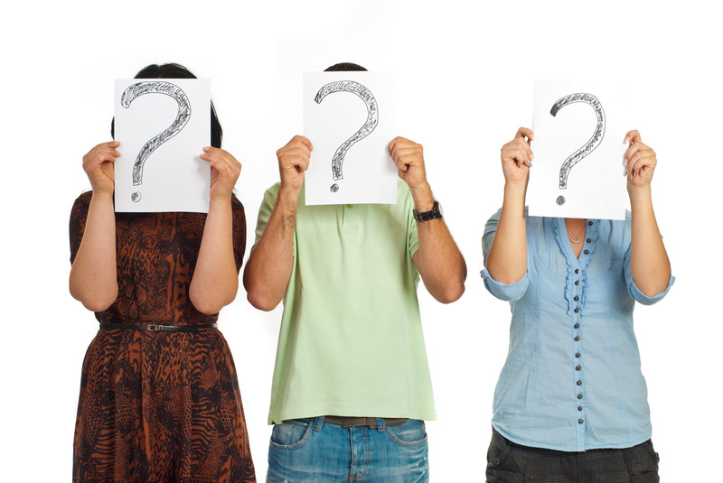 3 people holding up question marks in front of their faces stock image
